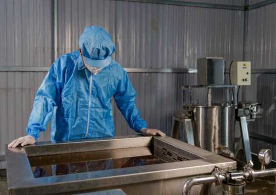 Worker in blue protective clothing monitors a rectangular stainless steel ultrasonic treatment tank at the LOPHA factory