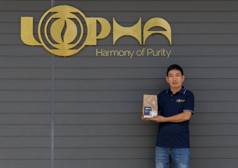 Người đàn ông đang cầm túi cà phê bên logo Lopha Coffee